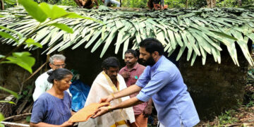 മാതൃദിനത്തോടനുബന്ധിച്ച് മൂന്നാംതോട് മുട്ട് കടവിലെ രാമന്‍ - കമല ദമ്പതികളെ ഗിരീഷ് തേവള്ളി ആദരിക്കുന്നു. സമീപത്ത്ബിജെപി പ്രവര്‍ത്തകര്‍ വീടിന്റെ മേല്‍ക്കര കെട്ടുന്നു