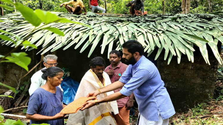 മാതൃദിനത്തോടനുബന്ധിച്ച് മൂന്നാംതോട് മുട്ട് കടവിലെ രാമന്‍ - കമല ദമ്പതികളെ ഗിരീഷ് തേവള്ളി ആദരിക്കുന്നു. സമീപത്ത്ബിജെപി പ്രവര്‍ത്തകര്‍ വീടിന്റെ മേല്‍ക്കര കെട്ടുന്നു