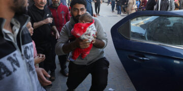 A man holds a baby as wounded Palestinians are rushed into Nasser hospital following Israeli strikes, amid the ongoing conflict between Israel and the Palestinian Islamist group Hamas, in Khan Younis in the southern Gaza Strip, December 4, 2023. REUTERS/Ibraheem Abu Mustafa