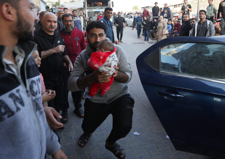 A man holds a baby as wounded Palestinians are rushed into Nasser hospital following Israeli strikes, amid the ongoing conflict between Israel and the Palestinian Islamist group Hamas, in Khan Younis in the southern Gaza Strip, December 4, 2023. REUTERS/Ibraheem Abu Mustafa