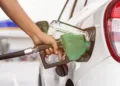 Hand holding fuel nozzle to refuel gasoline for car at petrol filling station