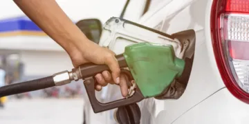 Hand holding fuel nozzle to refuel gasoline for car at petrol filling station