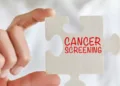 Businesswoman holding jigsaw puzzle pieces with Cancer screening text