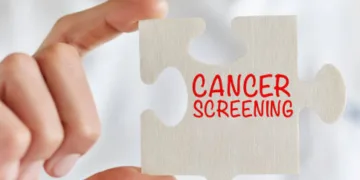 Businesswoman holding jigsaw puzzle pieces with Cancer screening text