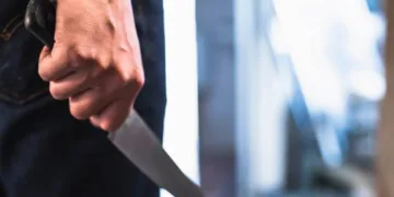 image of a robbers hands holding a knife in the shadows.