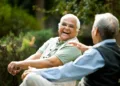 Two retired elderly men sitting on a park bench and having fun