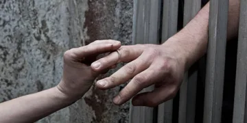 Lover putting wedding ring on prisoner hand