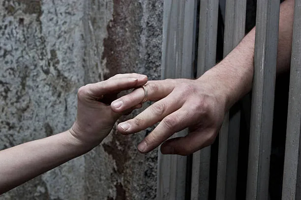 Lover putting wedding ring on prisoner hand