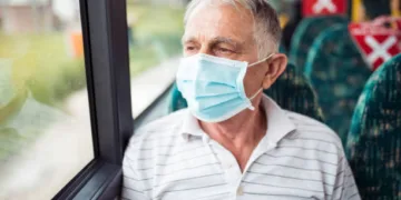 Senior man with respiratory mask traveling in the public transport by bus
