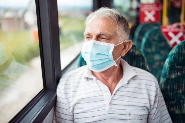 Senior man with respiratory mask traveling in the public transport by bus