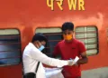 A railway conductor (L) checks the documents of a passenger who arrived to board on a train after the government eased restrictions imposed as a preventive measure against the COVID-19 coronavirus, at Kalupur railway station in Ahmedabad on June 1, 2020. (Photo by SAM PANTHAKY / AFP)