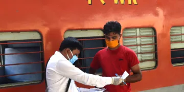 A railway conductor (L) checks the documents of a passenger who arrived to board on a train after the government eased restrictions imposed as a preventive measure against the COVID-19 coronavirus, at Kalupur railway station in Ahmedabad on June 1, 2020. (Photo by SAM PANTHAKY / AFP)