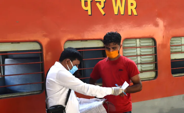 A railway conductor (L) checks the documents of a passenger who arrived to board on a train after the government eased restrictions imposed as a preventive measure against the COVID-19 coronavirus, at Kalupur railway station in Ahmedabad on June 1, 2020. (Photo by SAM PANTHAKY / AFP)