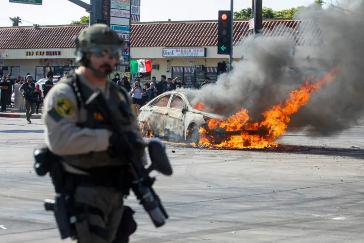 A car burns during a protest following federal immigration operations, in the Compton neighborhood of Los Angeles, California on June 7, 2025. US President Donald Trump deployed 2,000 troops on June 7, 2025 to handle escalating protests against immigration enforcement raids in the Los Angeles area, a move the state's governor termed "purposefully inflammatory." Federal agents clashed with angry crowds in a Los Angeles suburb as protests stretched into a second night Saturday, shooting flash-bang grenades and shutting part of a freeway amid raids on undocumented migrants, reports said. (Photo by RINGO CHIU / AFP)